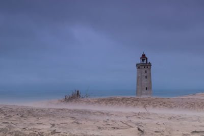 Lighthouse on beach against sky