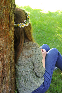 Woman wearing flowers while sitting on field