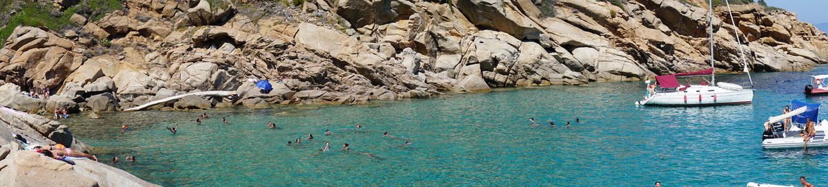 People on rock formation in sea