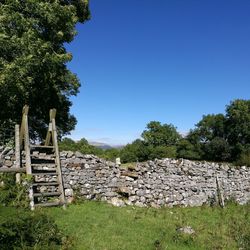 Stack of logs on landscape against clear sky