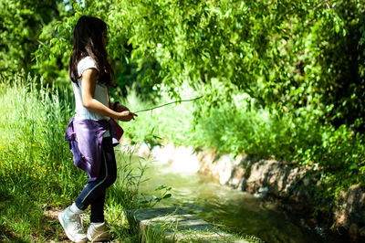 Side view of girl standing against plants