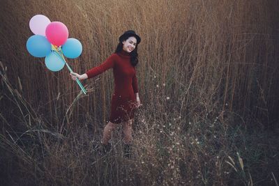 Portrait of woman with balloons on field