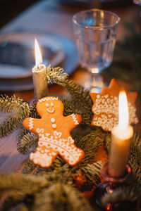 Close-up of gingerbread cookie on tree by illuminated candles