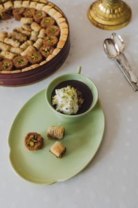 Drinking chocolate in matching green cup and plate with assorted baklava dessert tin