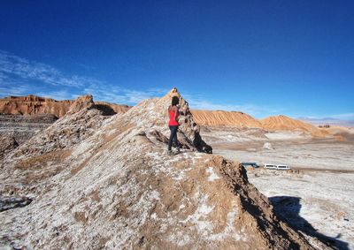 Rear view of men on rock against blue sky