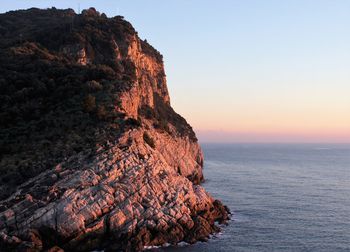 Rock formation by sea against sky during sunset