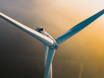 Close-up on the propellers of a wind turbine during a misty morning and sunrise. green energy. 