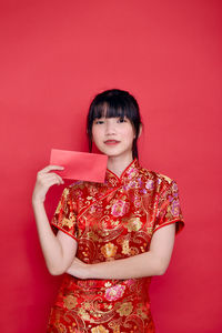 Portrait of a smiling young woman against red background