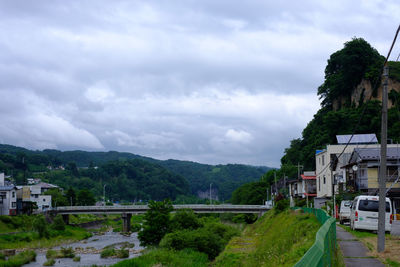 Trees and houses by buildings in city against sky