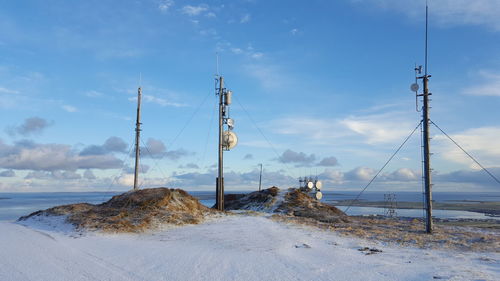 Electricity pylon on beach against sky