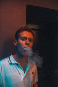 Portrait of young man smoking at home