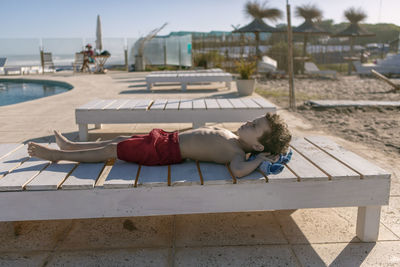 Child lying on pool deck chair