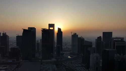 Modern buildings in city against sky during sunset