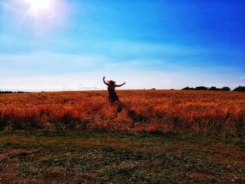 Woman jumping on field against sky