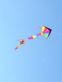 Low angle view of kite flying against clear blue sky