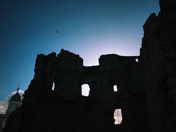 Low angle view of silhouette birds flying against clear sky