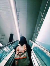 Rear view of woman standing on escalator