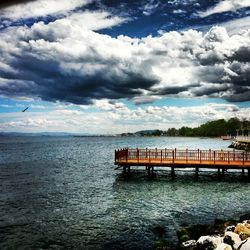 Pier on sea against cloudy sky