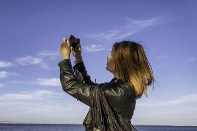 Side view of woman taking selfie standing against selfie