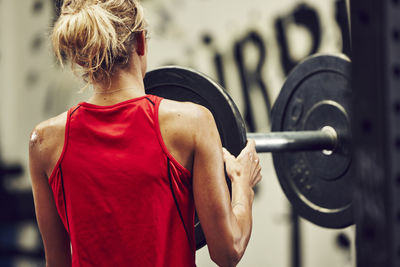 Young woman putting weight on barbell