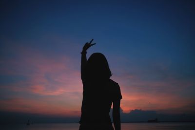 Silhouette woman standing by sea against sky during sunset