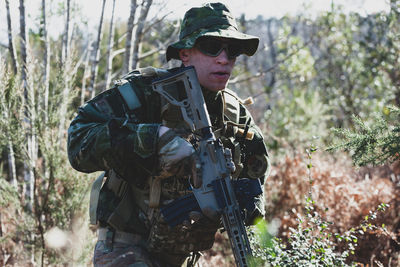 Airsoft military game player in camouflage uniform with armed assault rifle.