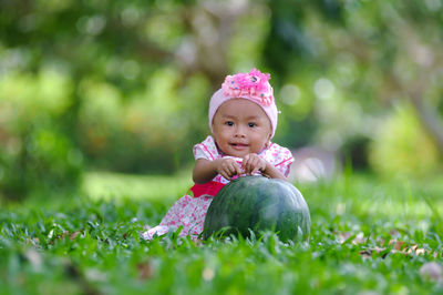 Portrait of cute baby girl sitting on field