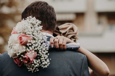 Rear view of groom embracing with bride outdoors