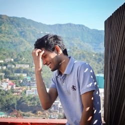 Smiling young man standing against mountains