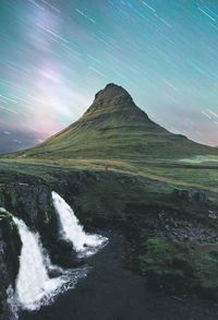 Scenic view of waterfall on mountain against star trail