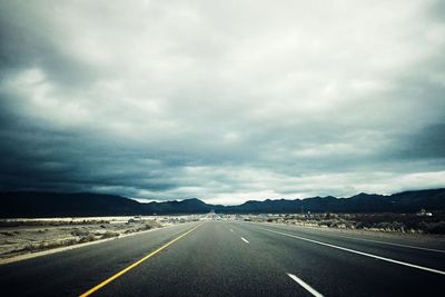 Surface level of road against cloudy sky