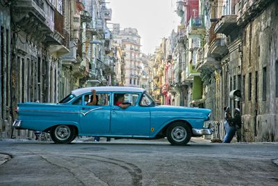 Vintage car on street by buildings in city