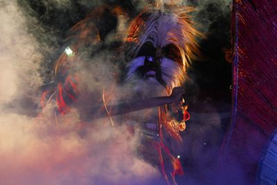 Person wearing mask in smoke at night