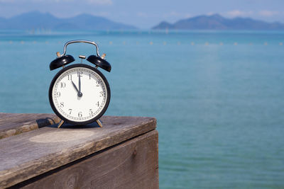 Close-up of clock on table against sea