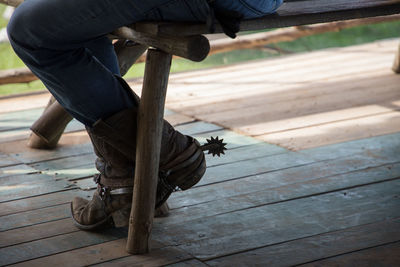 Low section of man wearing boots sitting on bench