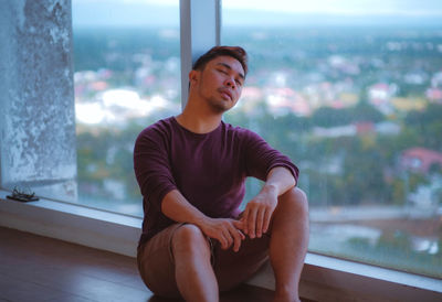 Young man sleeping by window at home