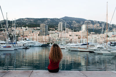 Rear view of woman in city at harbor against sky