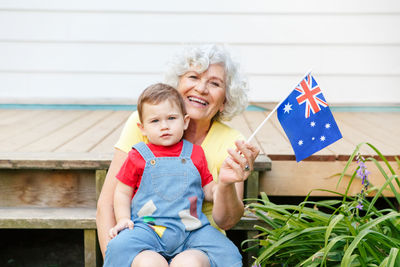 Senior woman holding flag sitting with son on steps