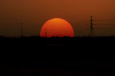 Silhouette electricity pylon against sky during sunset