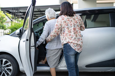 Rear view of woman standing in car