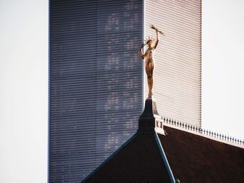 Low angle view of statue by building against sky