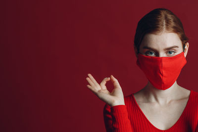 Portrait of young woman standing against yellow background