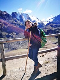 Full length portrait of woman standing against snowcapped mountains and sky