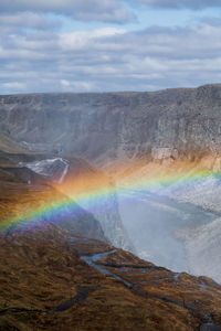 Scenic view of rainbow over landscape against sky