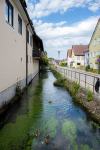 Canal amidst houses and buildings against sky