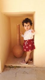 Portrait of cute girl standing against wall