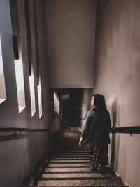 Rear view of woman standing on staircase in building