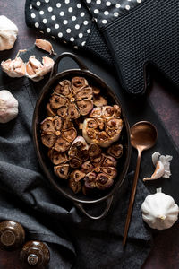 Roasted garlic bulbs fresh out of the oven, against a dark background.