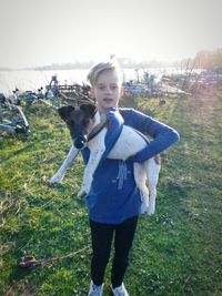 Portrait of boy with dog standing on field