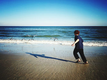 Full length of woman on beach against clear sky